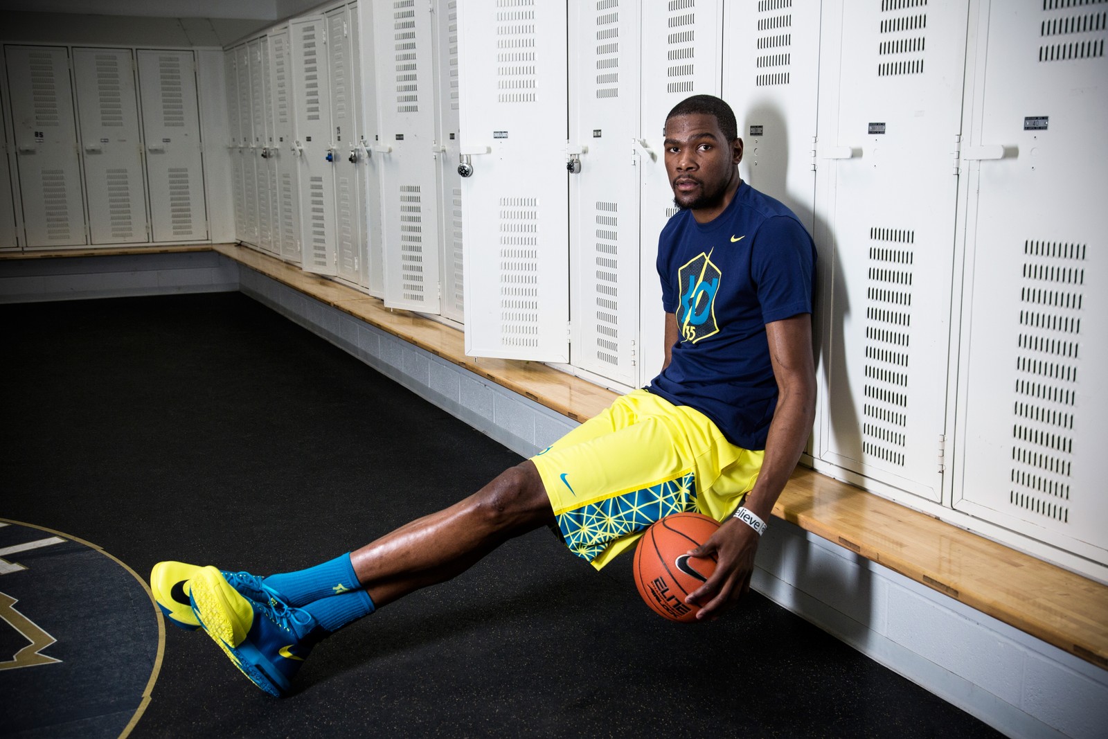 Um homem árabe sentado em um banco com uma bola de basquete na mão (basquetebol, amarelo, articulação, esportes, treinamento esportivo)