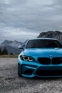 BMW Serie 4: Impactante coche deportivo azul contra un majestuoso fondo montañoso