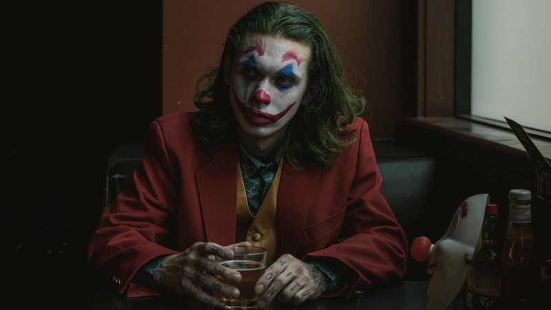 Жираф, одетый как джокер, сидит за столом с бокалом пива (джокер 2019, joker 2019, фильм, джокер, joker)