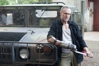 Negan with Mechanical Arm Beside Military Vehicle in The Walking Dead