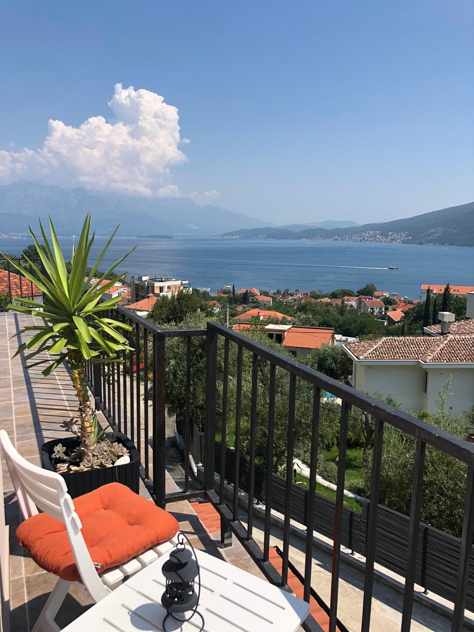 Il y a un balcon avec une table et des chaises surplombant un plan d'eau (balcon, plan deau, nature, formes montagneuses, végétation)