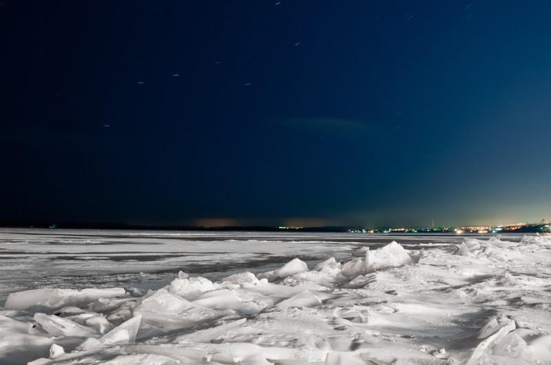 Снежная земля с кучей снега на ней и городом вдали (река волга, горизонт, замораживание, море, зима)