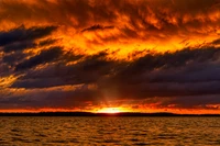 Atardecer ámbar sobre el agua con nubes dramáticas