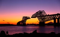 Sérénité crépusculaire : pont en silhouette contre un coucher de soleil vibrant