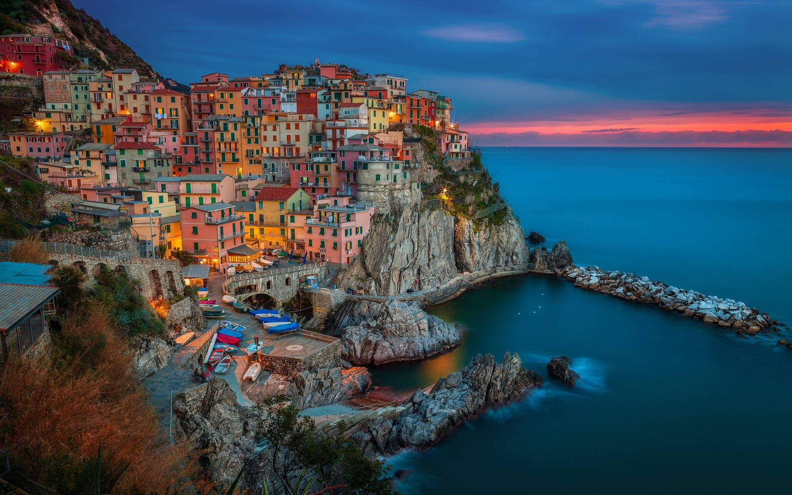 Uma vista de uma vila na costa ao pôr do sol (manarola, costa, mar, penhasco, turismo)