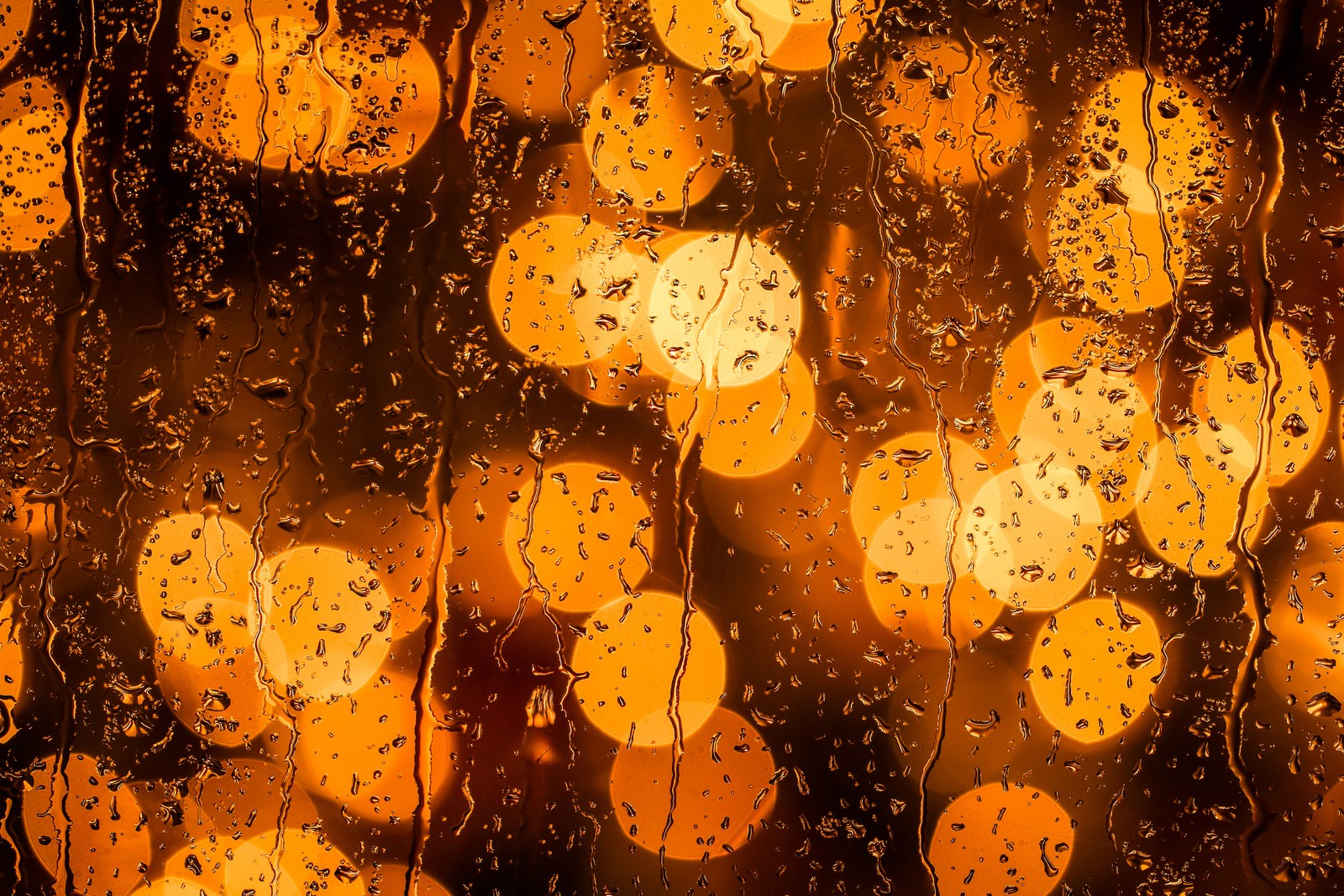 Um close de uma janela com gotas de chuva sobre ela (laranja, água, amarelo, âmbar, chuva)