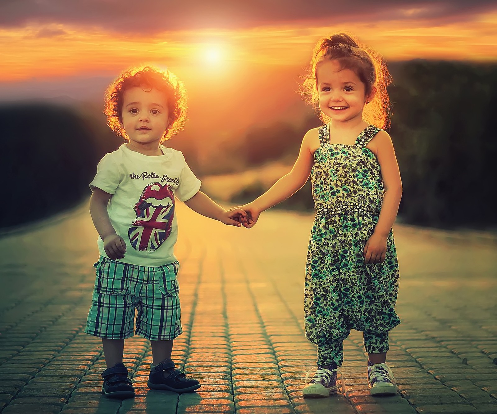 Duas crianças de mãos dadas em uma calçada de tijolos (fofo, crianças, amor)