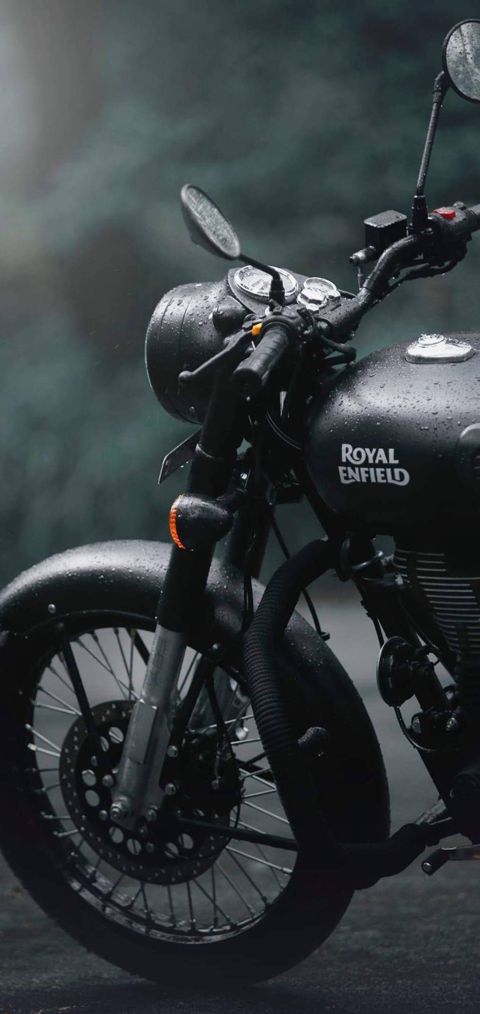 There is a black motorcycle parked on the street in the dark (royal, enfield)