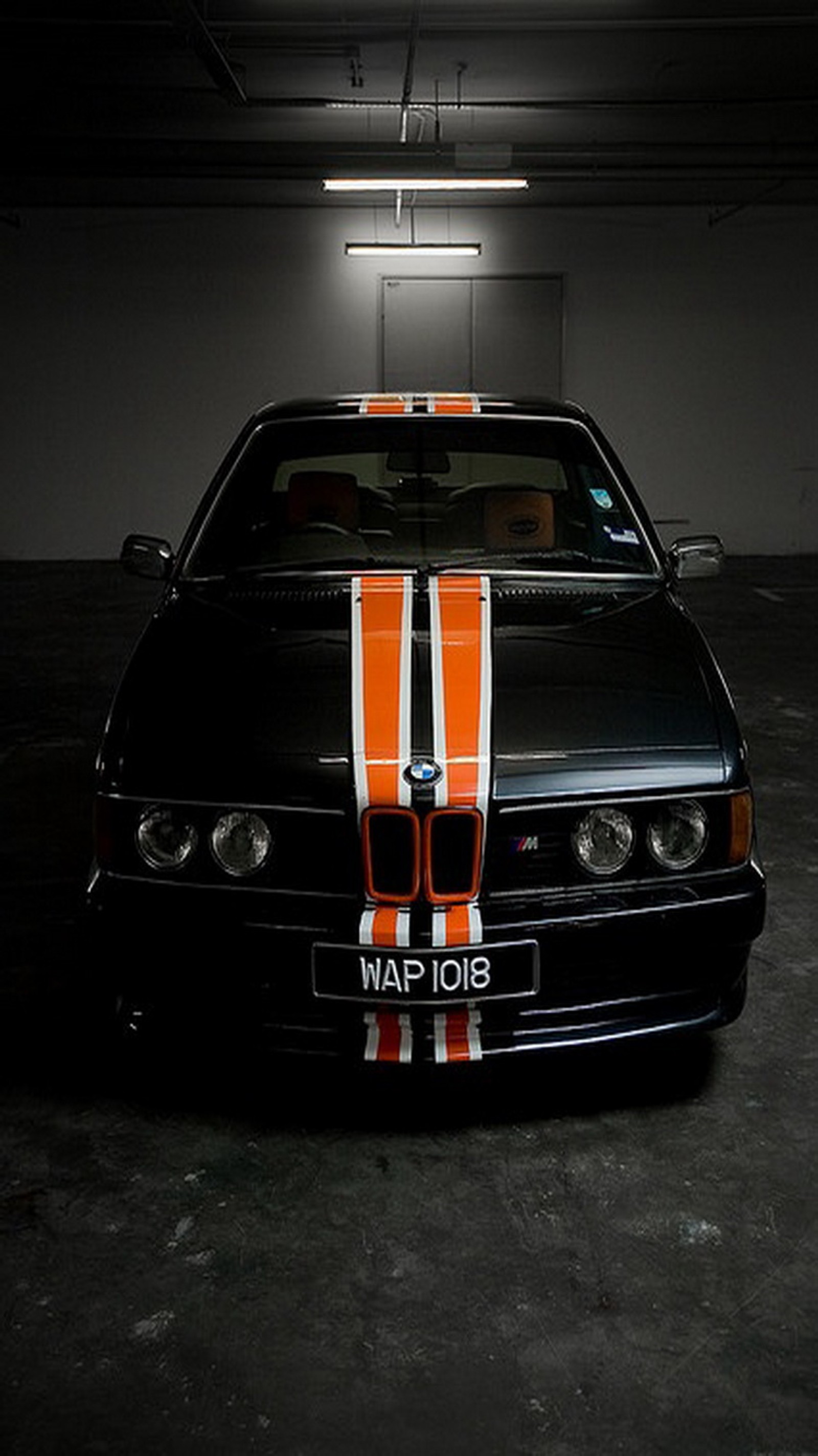 Arafed bmw car with orange and white stripes parked in a garage (black, bmw, bmw e24)