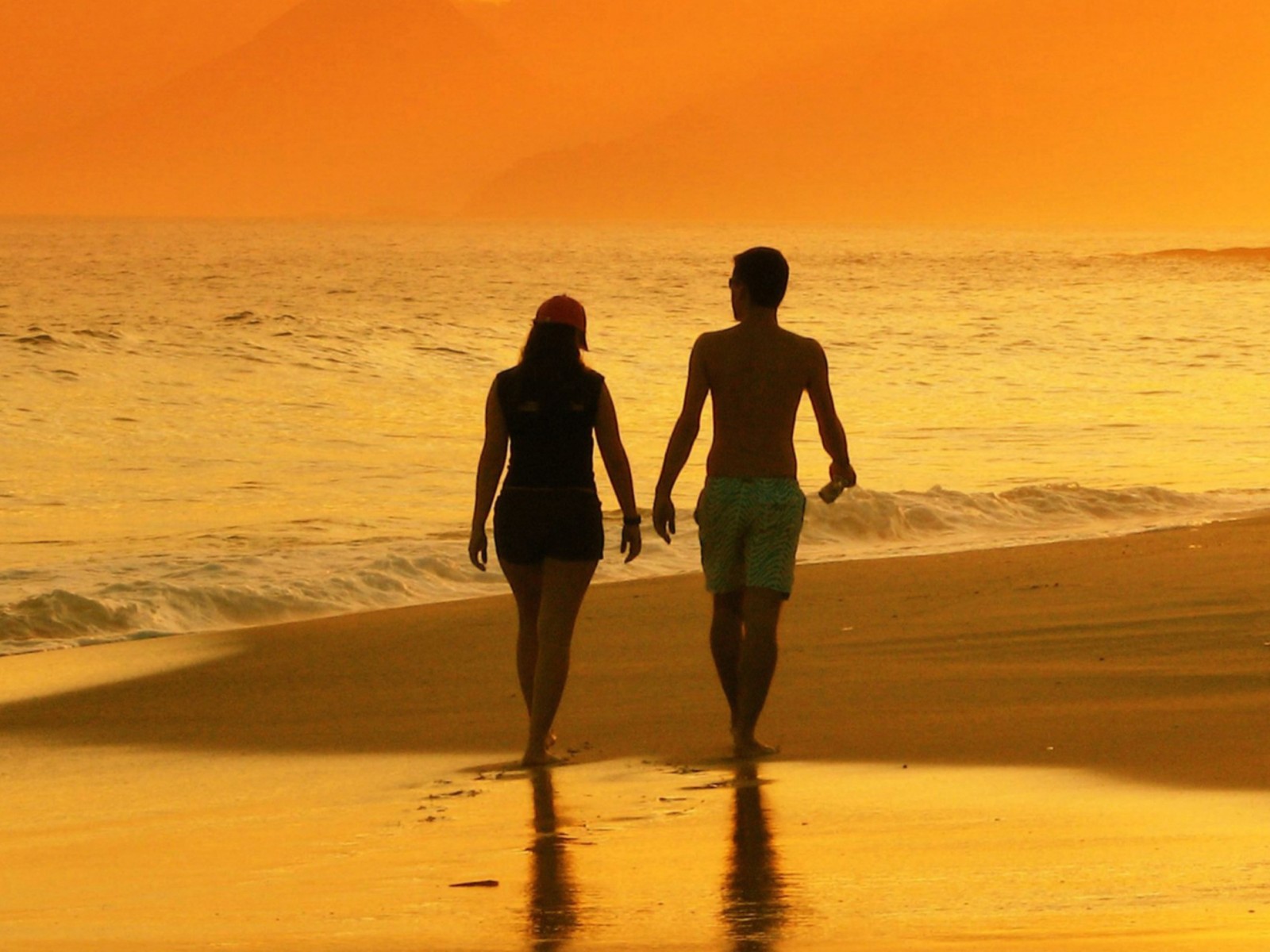 Deux personnes marchent sur la plage au coucher du soleil (couple, amour)