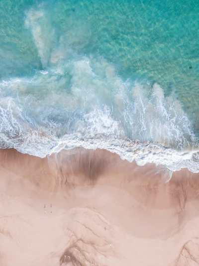 Luftaufnahme sanfter Wellen, die an einen Sandstrand plätschern