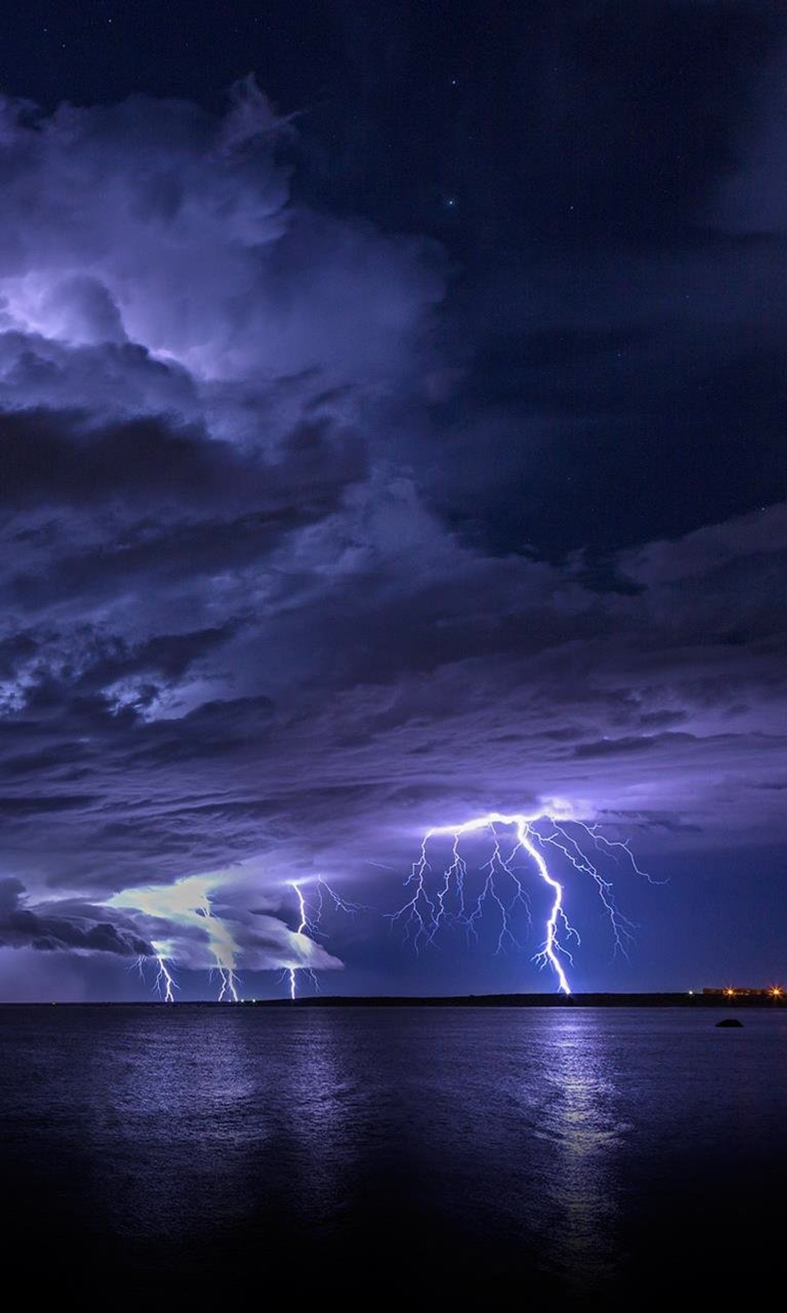 Des éclairs illuminent un plan d'eau sous un ciel nuageux. (paysage, nature, tempête)