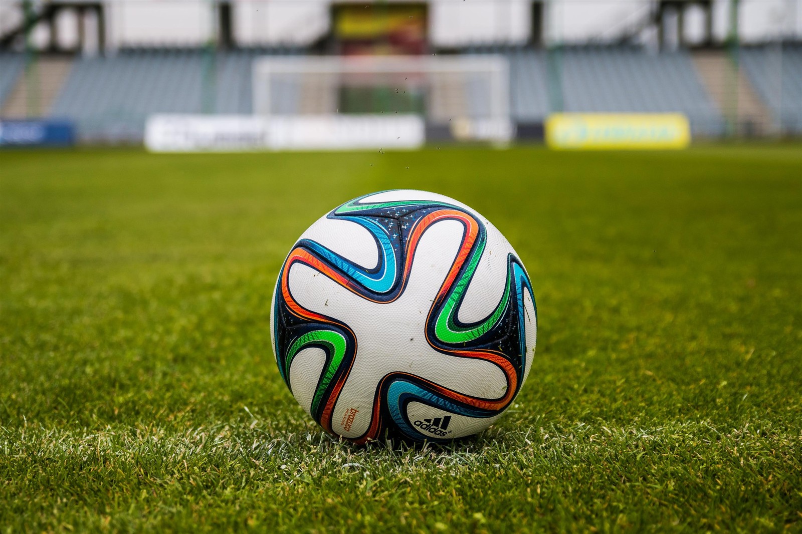 Há uma bola de futebol na grama de um estádio (campo de futebol, bola, estádio, bola de futebol, futebol)