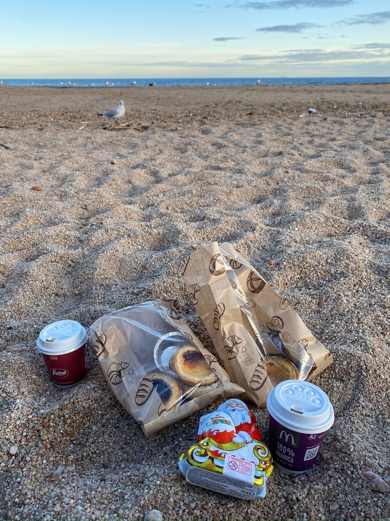 Две сумки с едой и две чашки кофе на пляже (песок, вода, почва, алюминиевая банка, пейзаж)