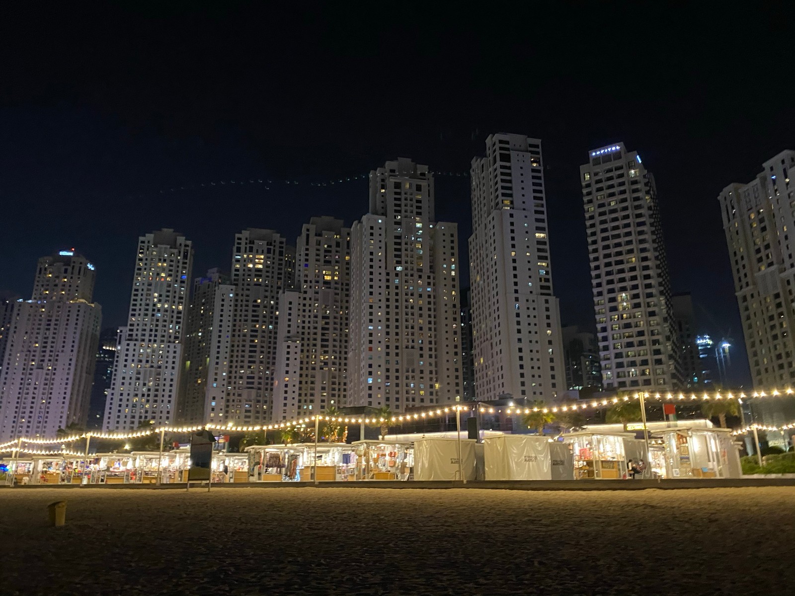 Vue nocturne d'une plage avec de nombreux bâtiments et lumières (dubaï, dubai, nuit, immeuble tour, ville)