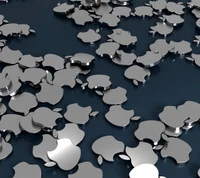 Logos Apple métalliques éparpillés sur une surface réfléchissante.