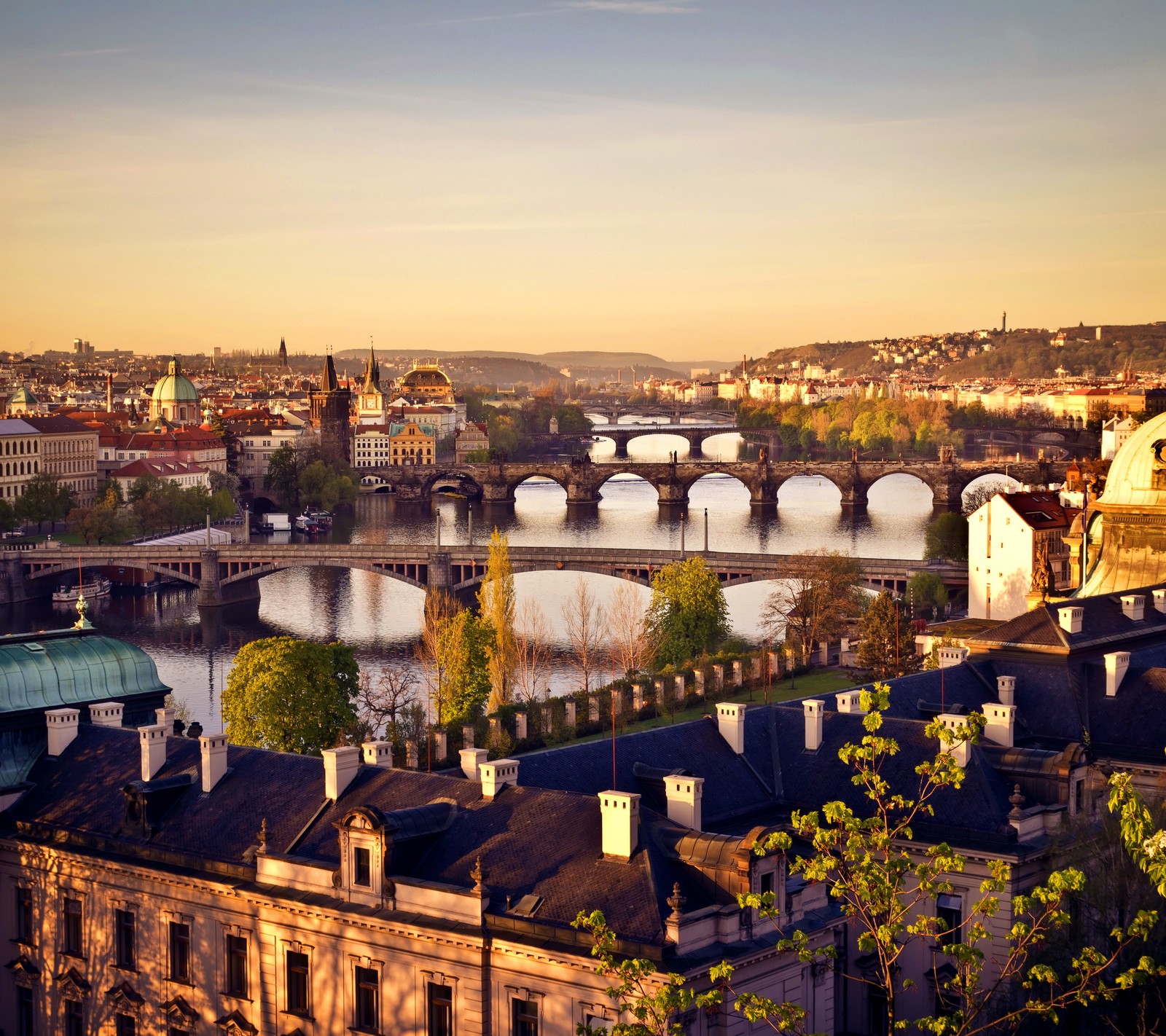 Arafed view of a city with a bridge and a river (country bulidings, landscape, nature, prague river czech, sunset)