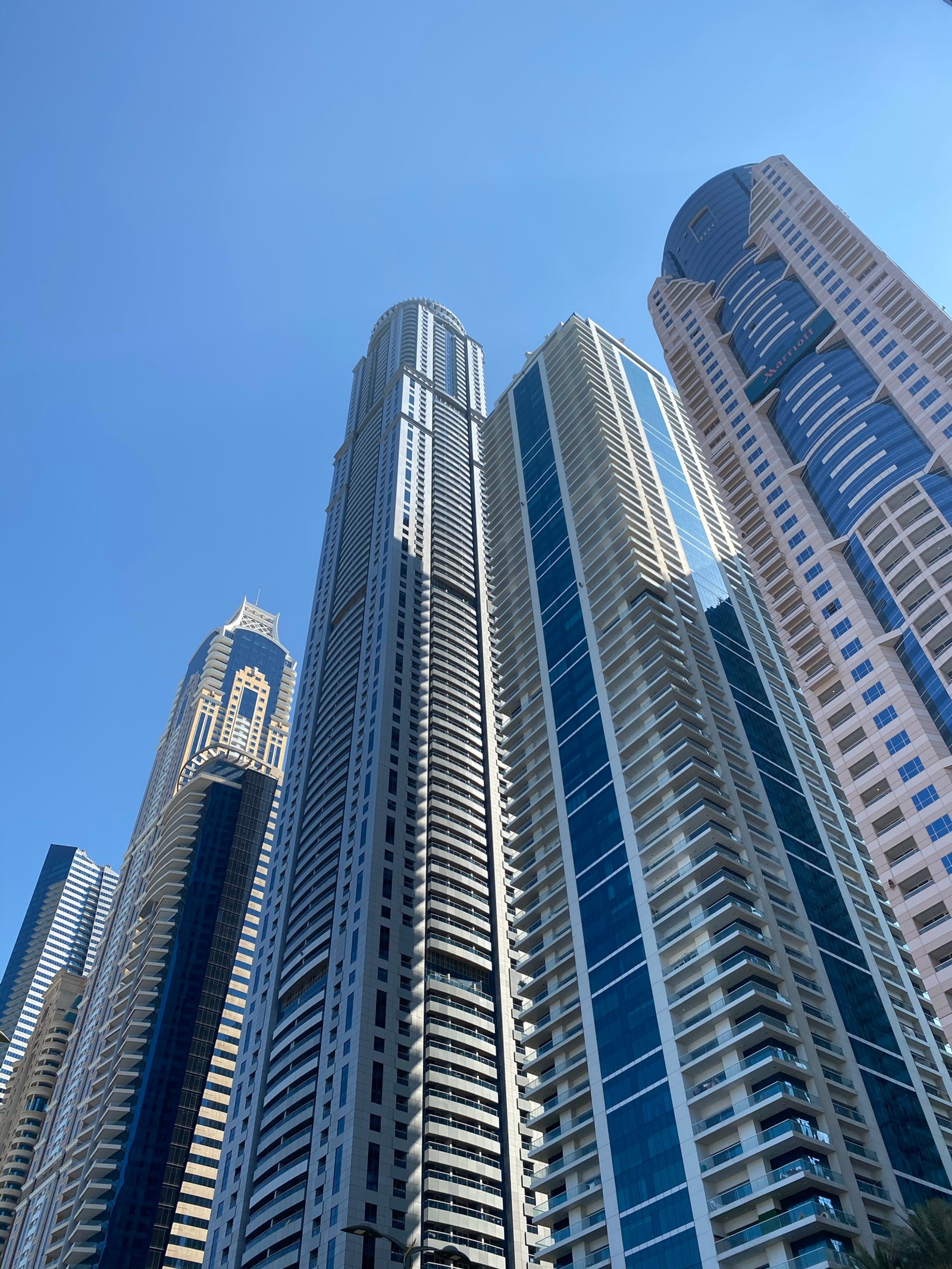 Des immeubles hauts dans une ville avec un ciel bleu en arrière-plan. (dubaï, dubai, bleu, immeuble tour, journée)