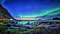 Impresionante Aurora iluminando un sereno paisaje costero