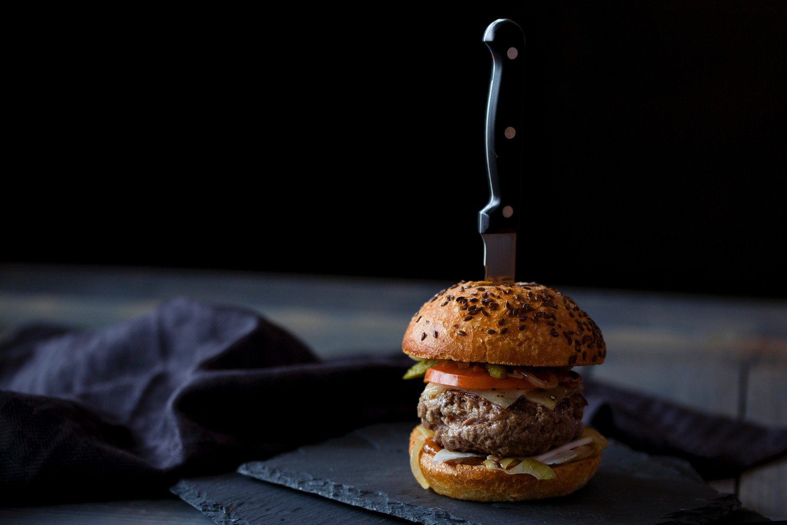 There is a hamburger with a knife on a cutting board (hamburger, restaurant, food, dish, cuisine)