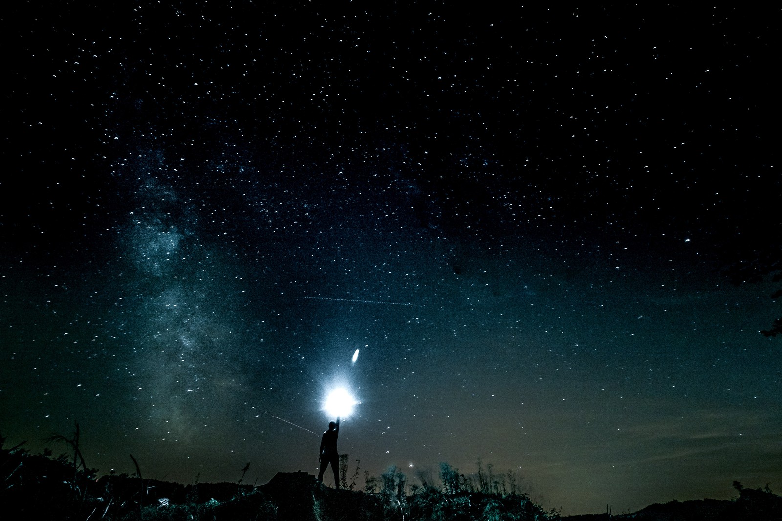 Sternenhimmel mit einer person, die ein licht hochhält. (nacht, atmosphäre, astronomisches objekt, stern, weltraum)