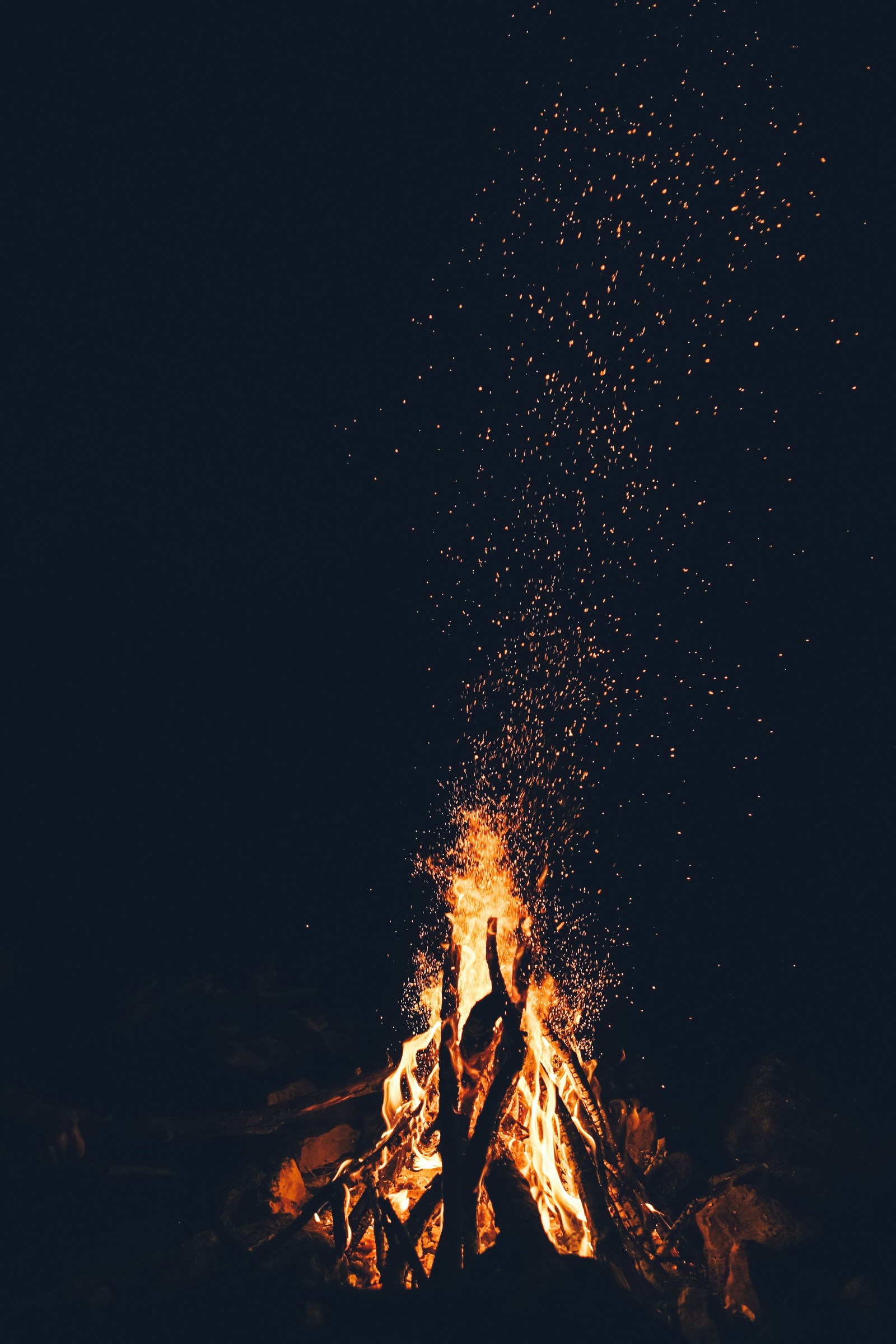 Há uma pessoa em pé na frente de um fogo com faíscas (ouro, vulcão, relaxamento, céu, lava)