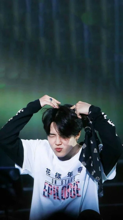 Jimin de BTS pose de manière ludique sur scène, attirant l'attention du public avec une expression charmante.