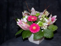 Bouquet de marguerites de Transvaal rose vif et de lys dans un vase élégant