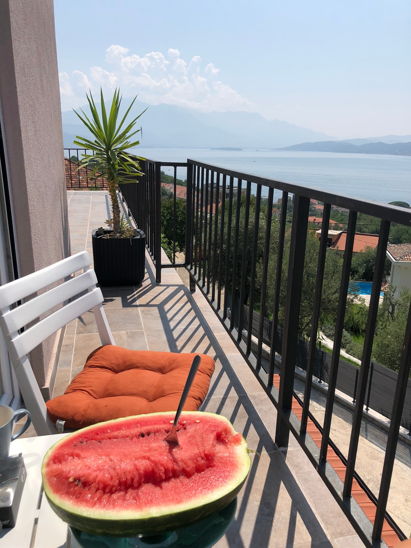 There is a watermelon on a table on a balcony (balcony, citrullus, muskmelon, peach, food)