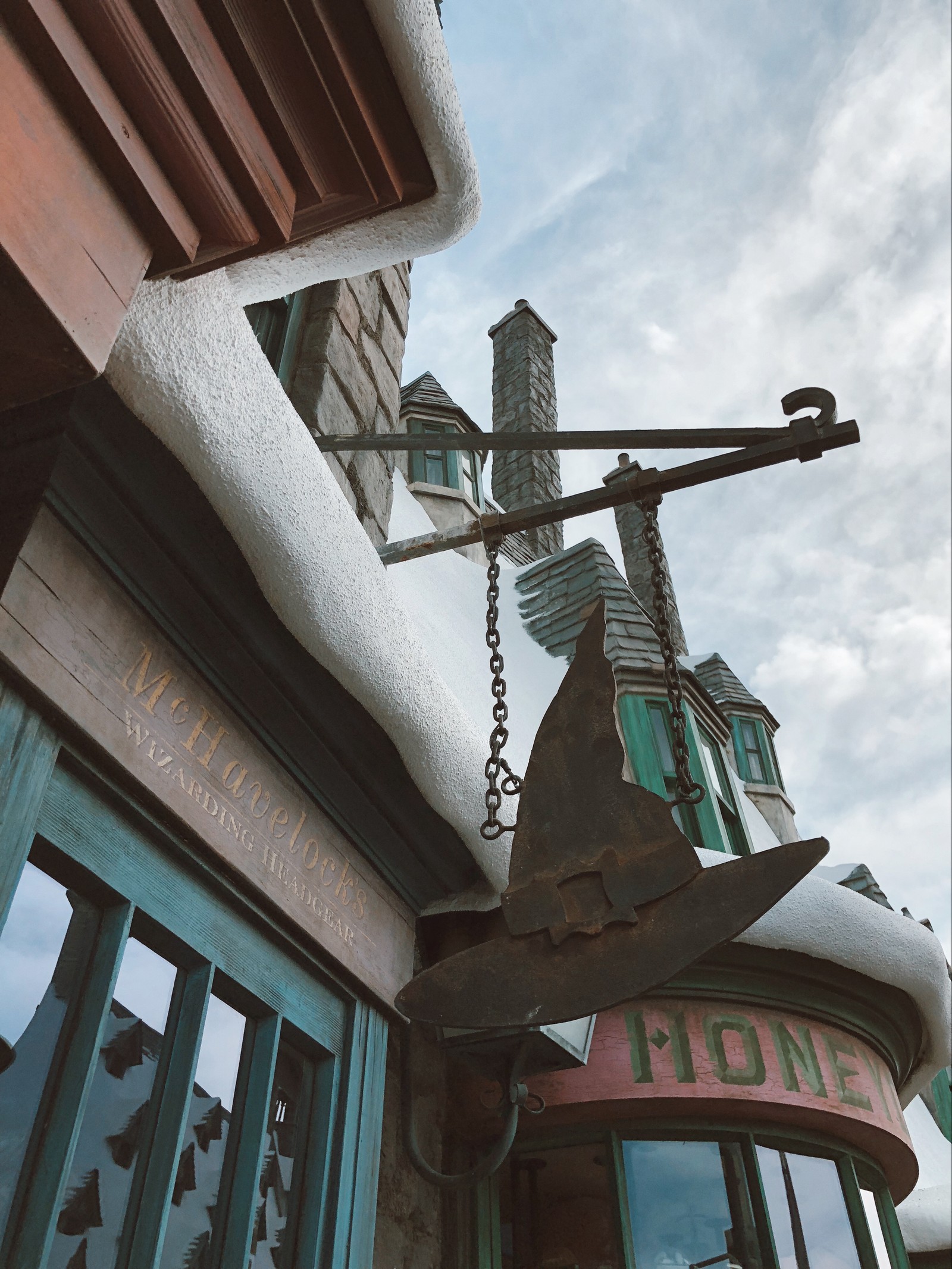 Ein schild, auf dem steht, dass die alte uhr am gebäude hängt (diagon alley, wahrzeichen, dach, bläulich grün, eisen)