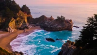 Crique côtière sereine avec des eaux turquoise vibrantes, des falaises rocheuses et une végétation luxuriante au coucher du soleil.