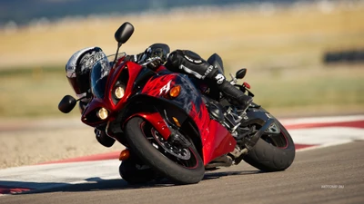 Piloto de motocicleta dinâmico inclinando-se em uma curva em uma pista de corrida, exibindo uma supermoto vermelha elegante e um capacete estiloso.