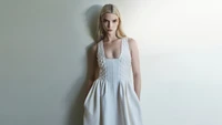 Anya Taylor-Joy em um vestido branco minimalista contra um fundo suave.