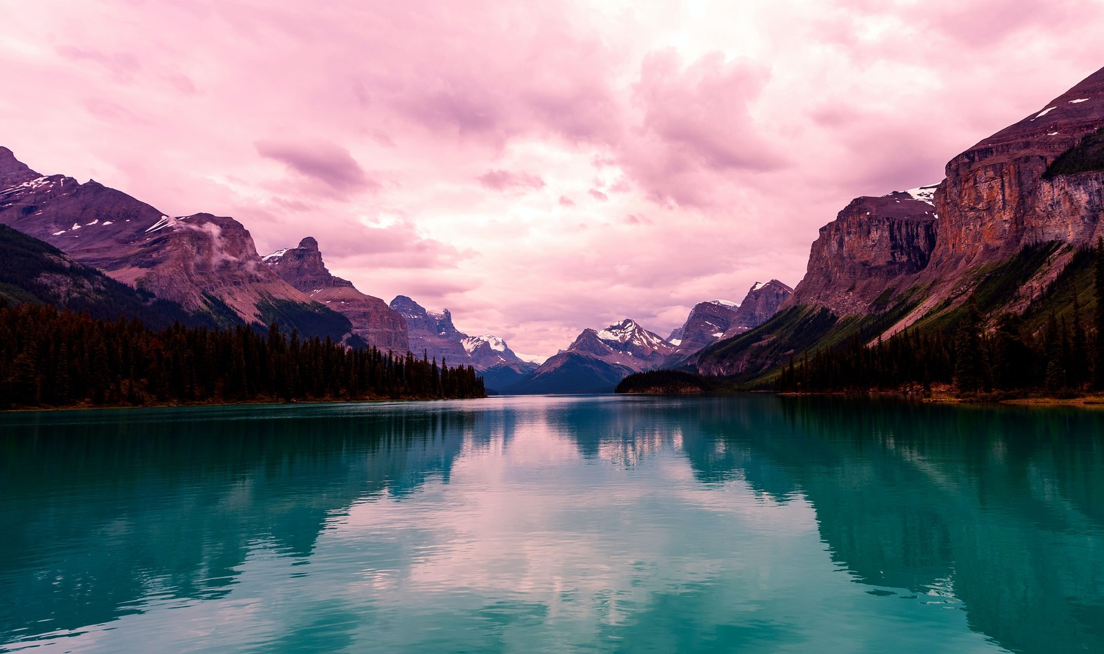 Montanhas e um corpo de água com um barco no meio (lago maligne, estética, canadá, céu roxo, cadeia de montanhas)