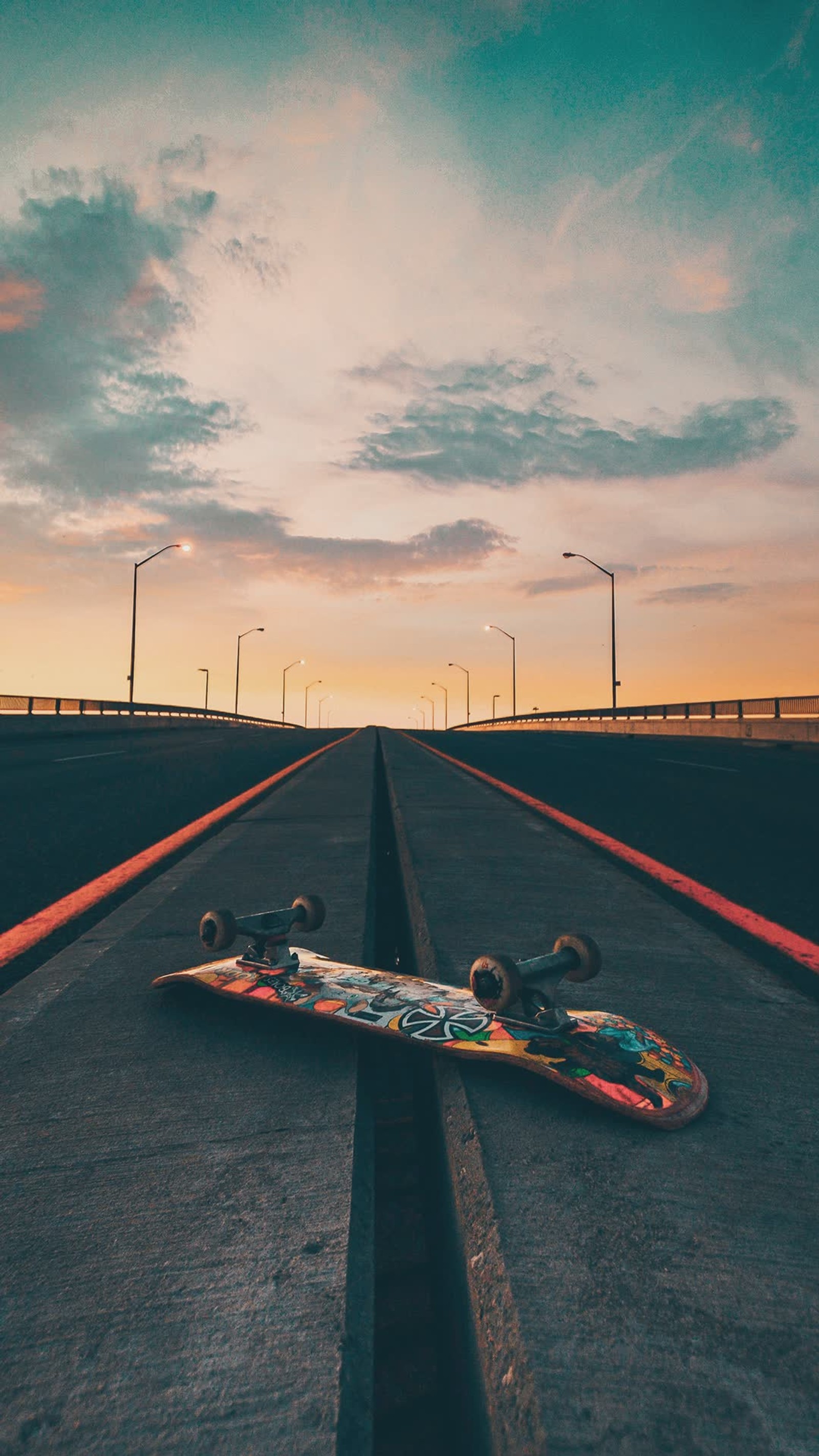 Arafed skateboard laying on the road with a sunset in the background (board, road, skateboard, skateboarding, skates)