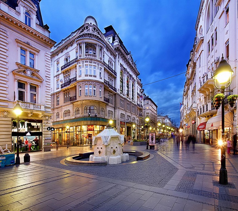 Une vue floue d'une rue de la ville avec une fontaine et des bâtiments (abej, beograd, knez mihajlova)