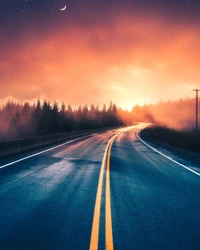 Une route sinueuse à travers une forêt brumeuse sous un ciel de coucher de soleil vibrant.