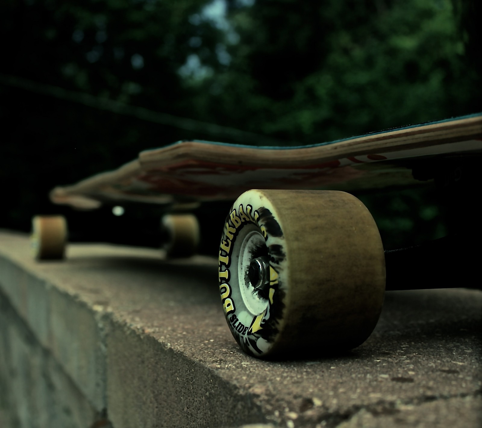 Um close de um skate parado em uma borda com árvores ao fundo (lg g3, longboard)