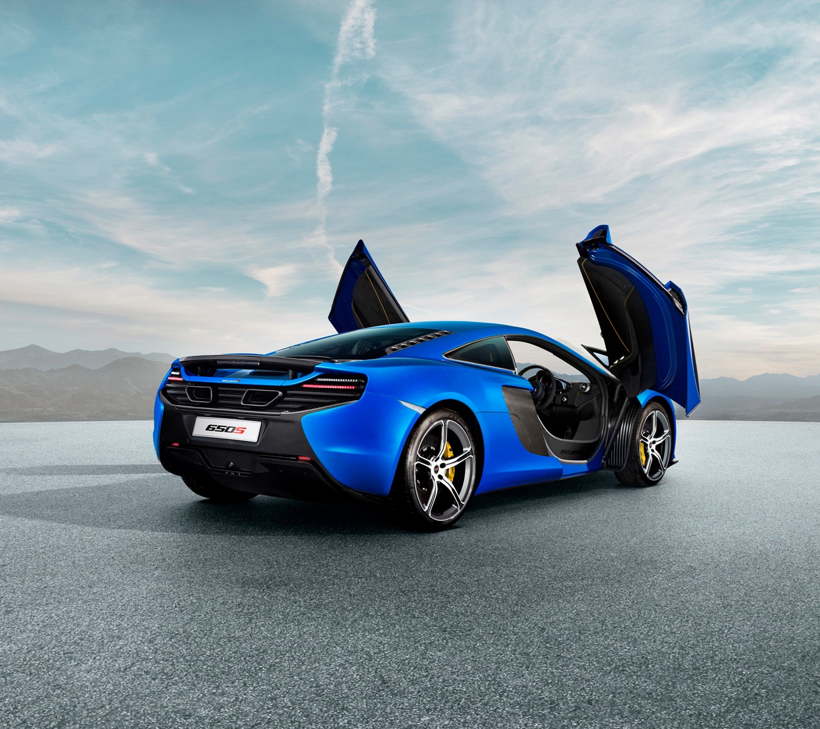 A blue sports car with open doors on a road (650s, auto, car, door, mclaren)