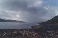 Fjord serein des Highlands avec une côte rocheuse et un ciel nuageux