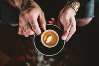 Espresso habilement préparé avec un design de feuille dans des mains tatouées