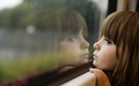 Menina contemplativa olhando pela janela