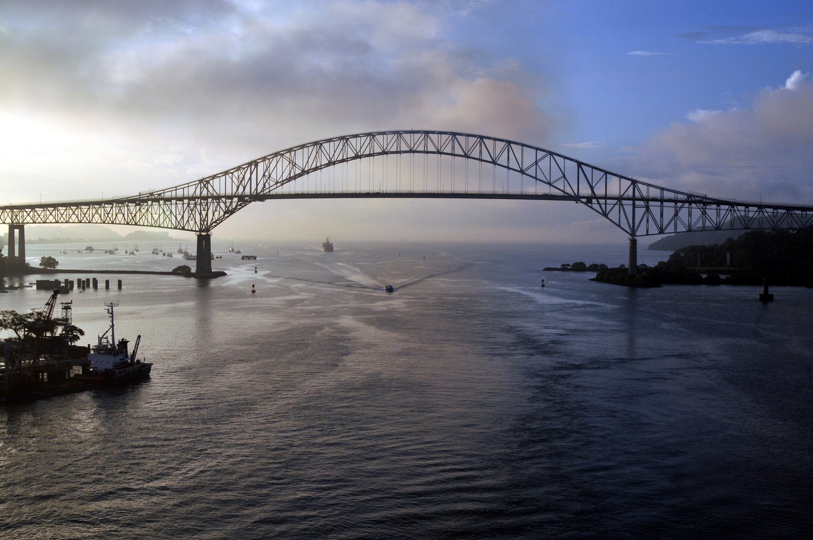 Uma vista de uma ponte sobre a água com barcos passando por baixo (ponte, flúmen, ponte arqueada, via navegável, nuvem)