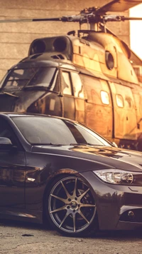 BMW 3 Series E90 in front of a helicopter at sunset.