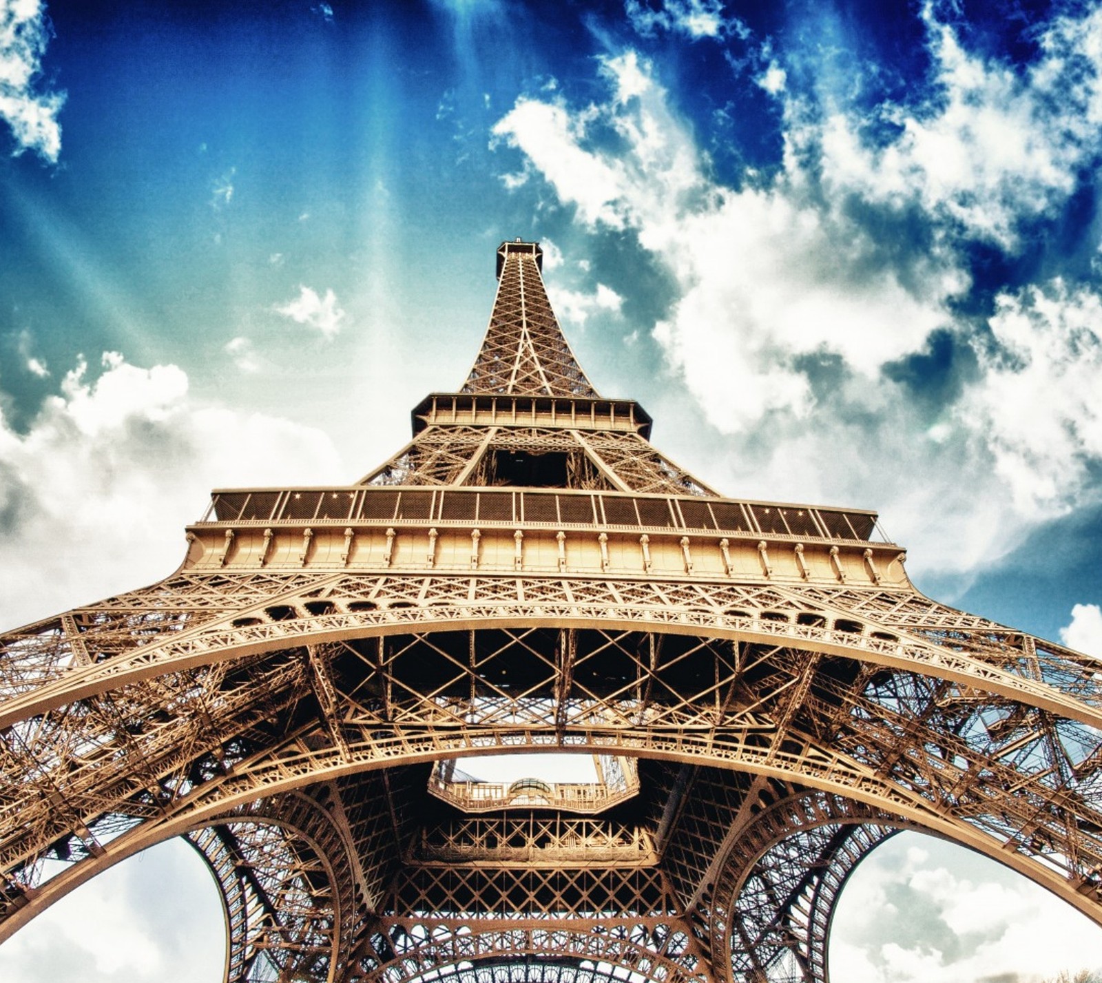 Um close-up do topo da torre eiffel com um céu azul ao fundo (frança, paris, céu, torre eiffel)