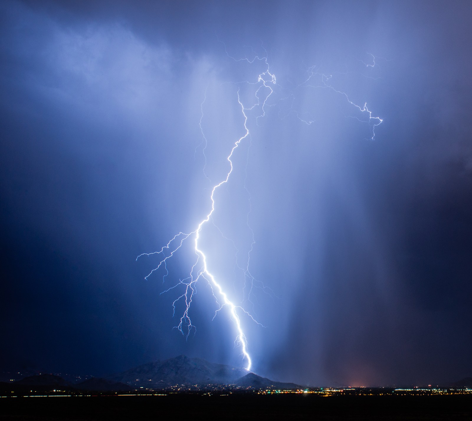 Lightning strikes through the sky over a city at night (storm, thunders)