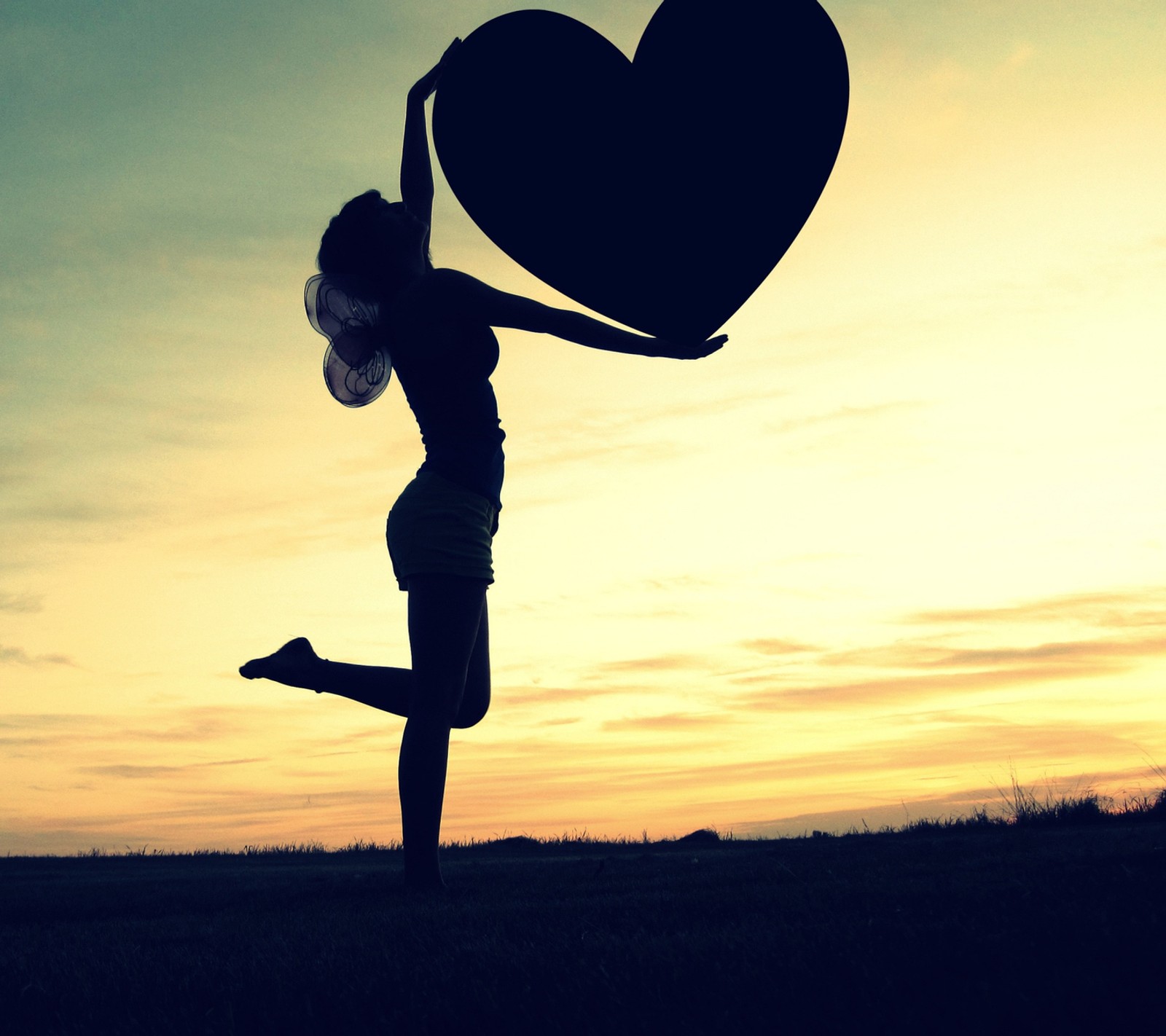 Silhouette d'une femme tenant un objet en forme de cœur dans les airs (cœur, amour)