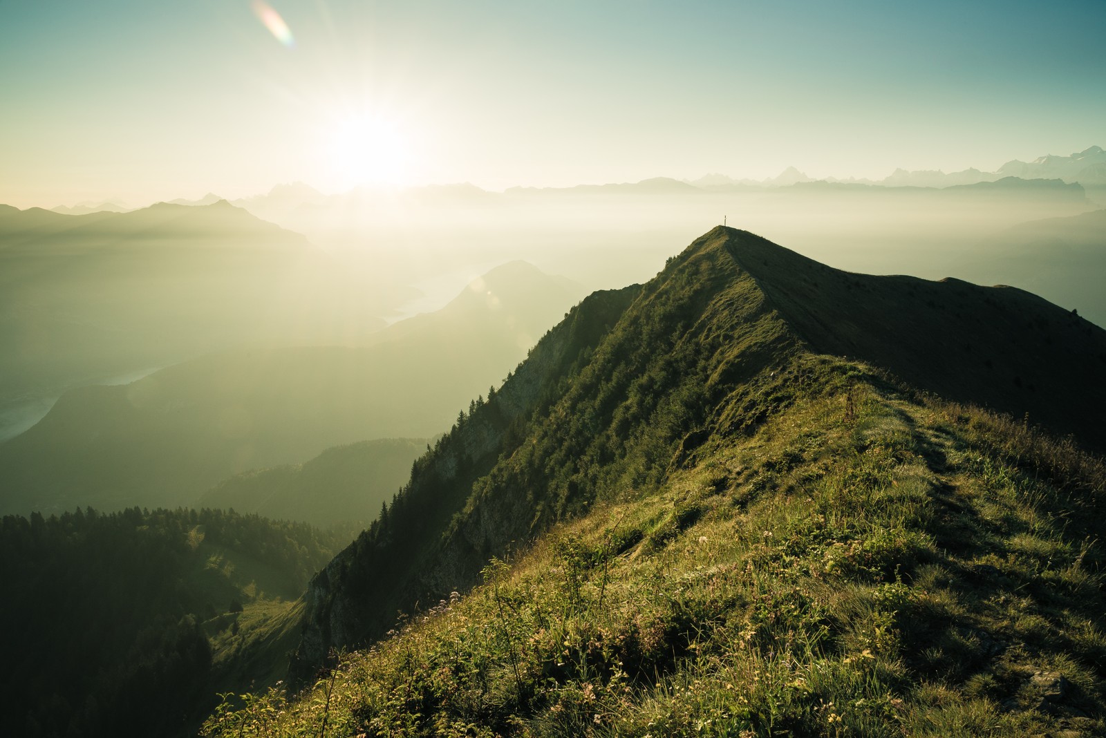 Visão aérea de uma montanha com uma encosta gramada e o sol (montanha, cadeia de montanhas, formas montanhosas, terras altas, natureza)