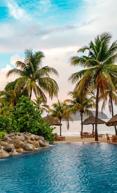 Tranquil Azure Pool Surrounded by Lush Palms and Beachside Huts