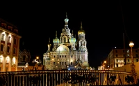 Beleuchtete Kirche des Erlösers am Blut bei Nacht in einer geschäftigen städtischen Umgebung